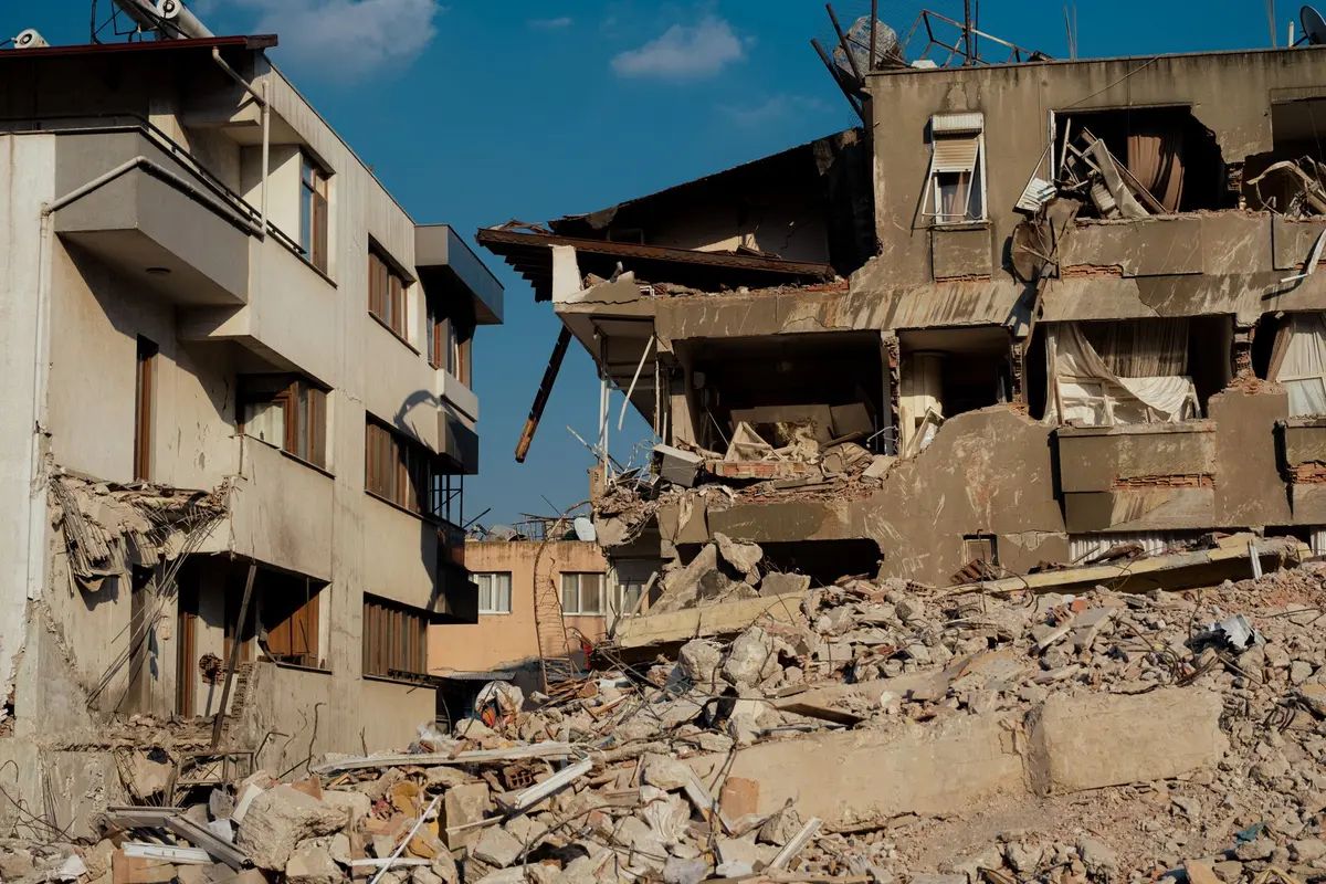 Escombros de edificios derrumbados y trabajadores de rescate en zona montañosa tras el terremoto