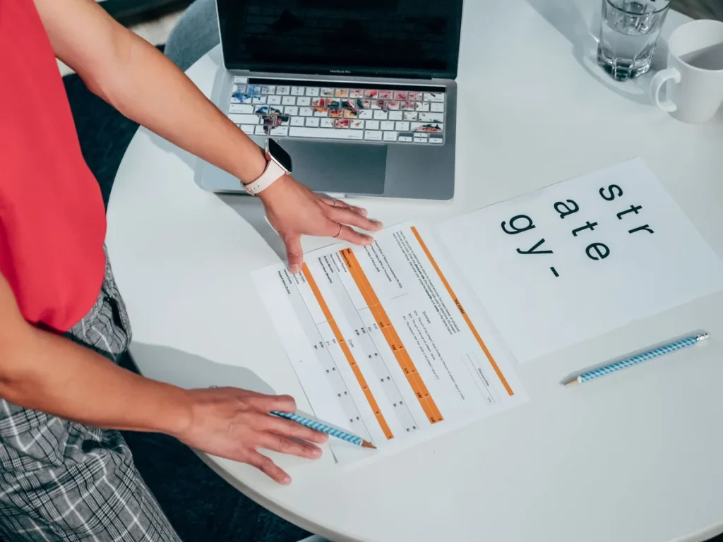 Hands organizing CRM proposal documents and evaluation criteria on a conference table