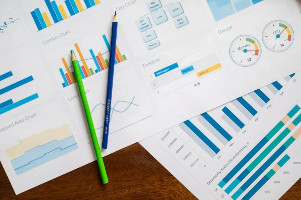 Analyst reviewing downward-trending economic charts and financial data on desk with documents and globe