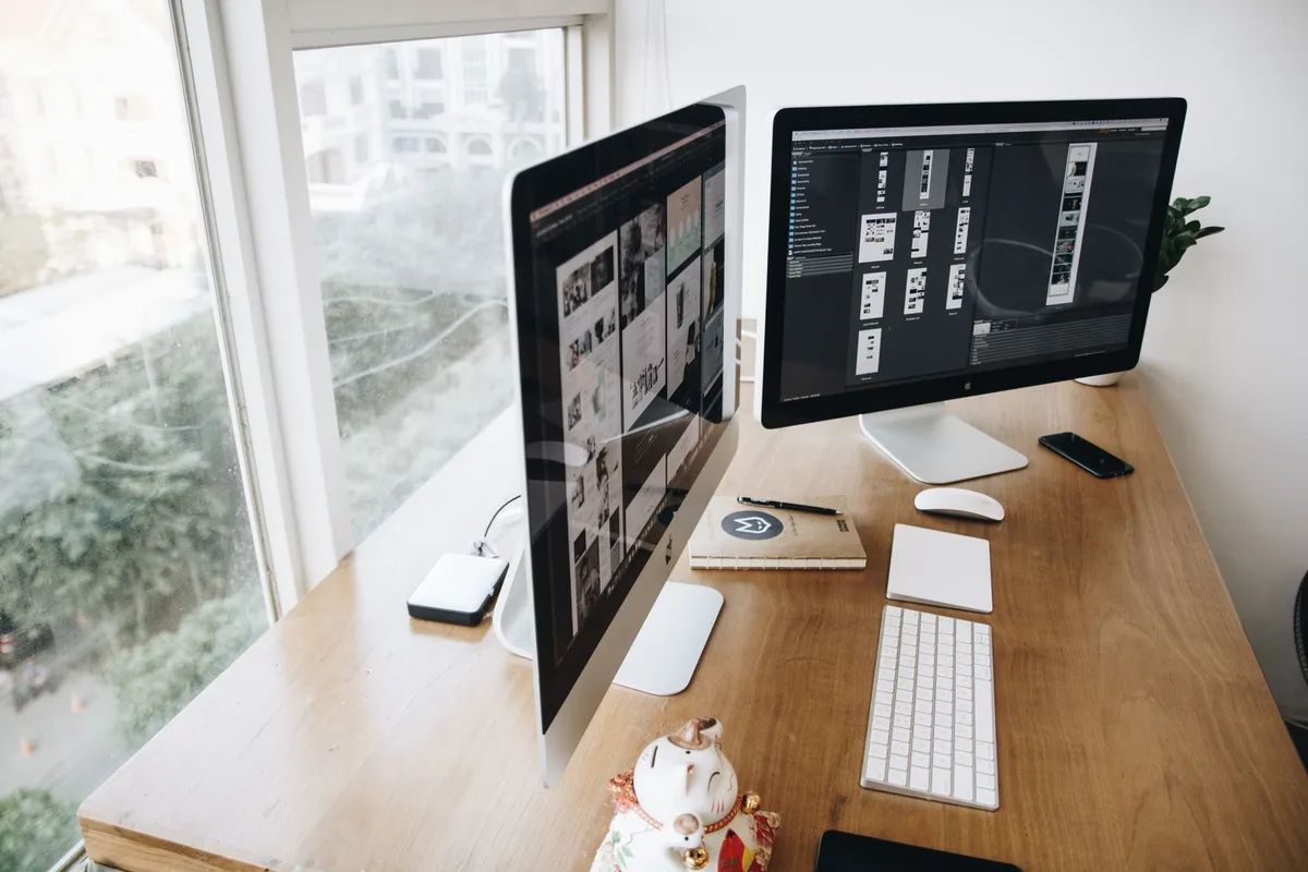 Insurance agent working at desk with multiple computer screens displaying CRM software and customer data
