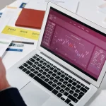 Laptop screen showing analytics charts and performance metrics on a workspace desk