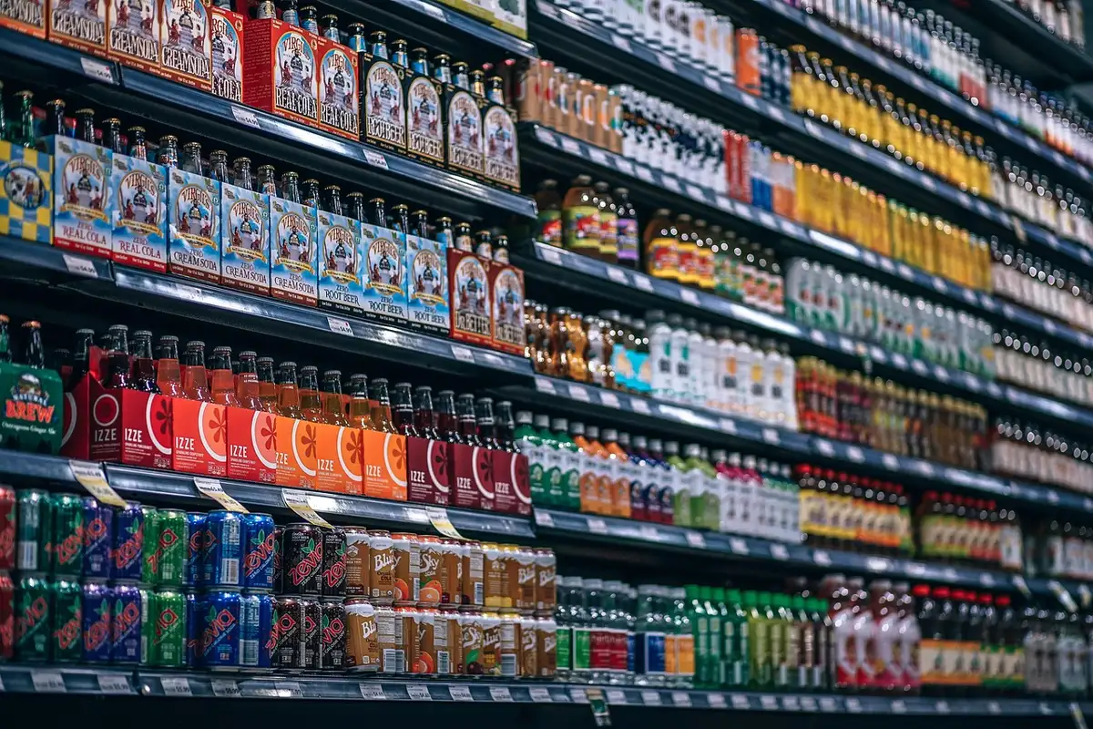 Botellas de cerveza importada en estantería de supermercado mostrando variedad de marcas