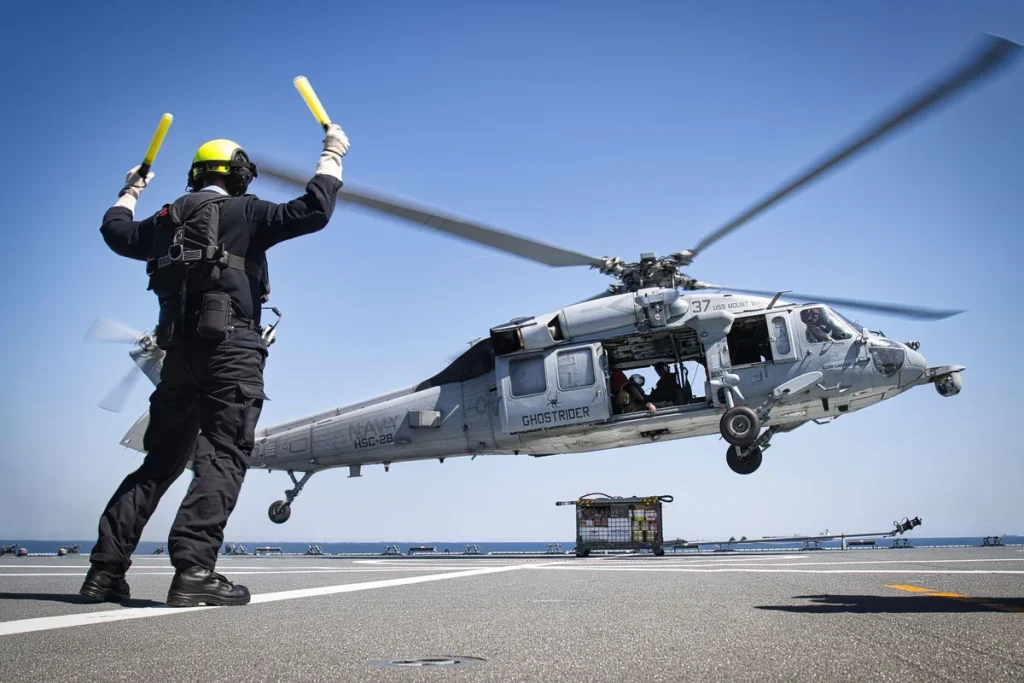 Military helicopter conducting naval operation over disabled container ship in Gulf of Oman