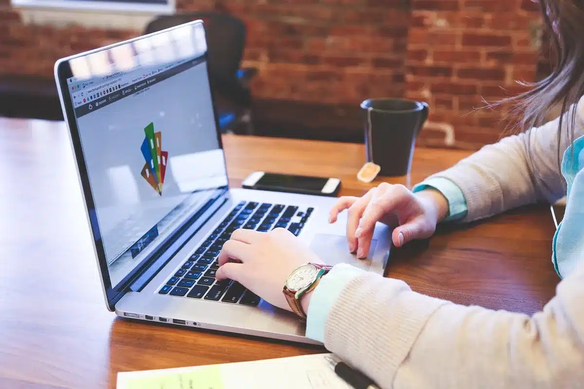 Hands adjusting budget sliders and cost metrics on a laptop screen in an office setting
