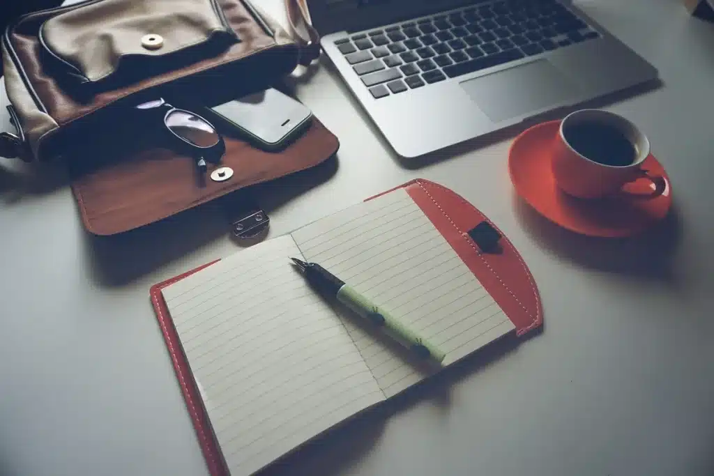 Creator workspace with laptop, notepad and hand holding a stylus