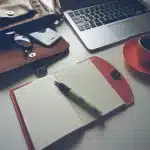 Creator workspace with laptop, notepad and hand holding a stylus