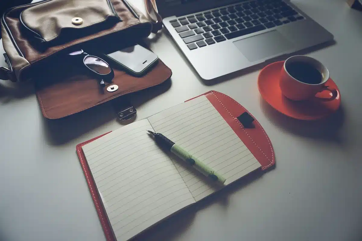 Creator workspace with laptop, notepad and hand holding a stylus