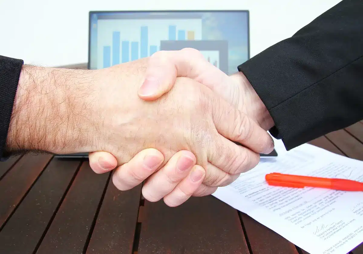 Silhouettes of two leaders shaking hands at a summit table