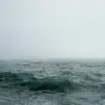 Offshore supply vessels near rocky islands under foggy sky, suggesting South Atlantic logistics tension