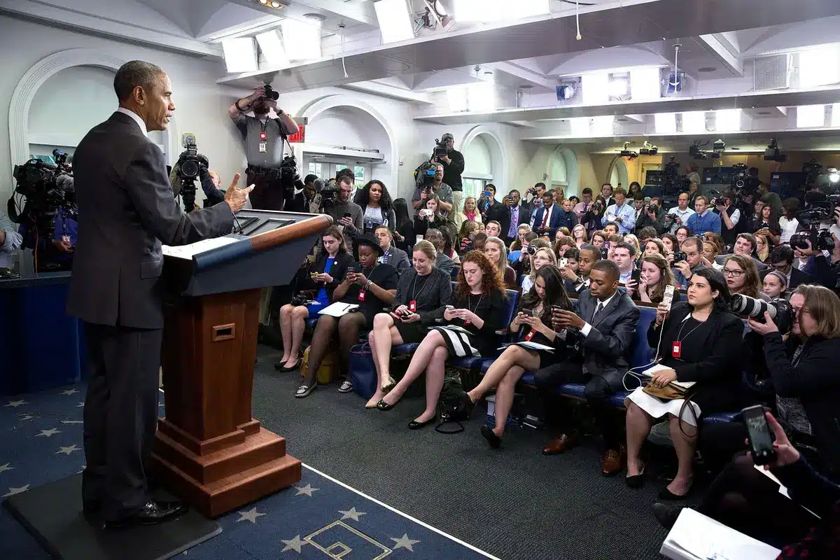 A speaker at a media conference addressing journalists and cameras