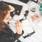 Solopreneur working at desk with LinkedIn interface on laptop screen and analytics notes