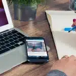 Laptop on a desk with blurred search results, notepad and coffee in a bright workspace