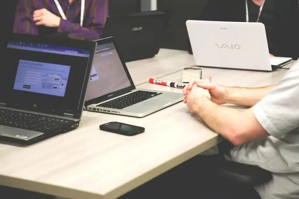 Hands at a laptop with printed keyword lists and an analytics printout on a desk