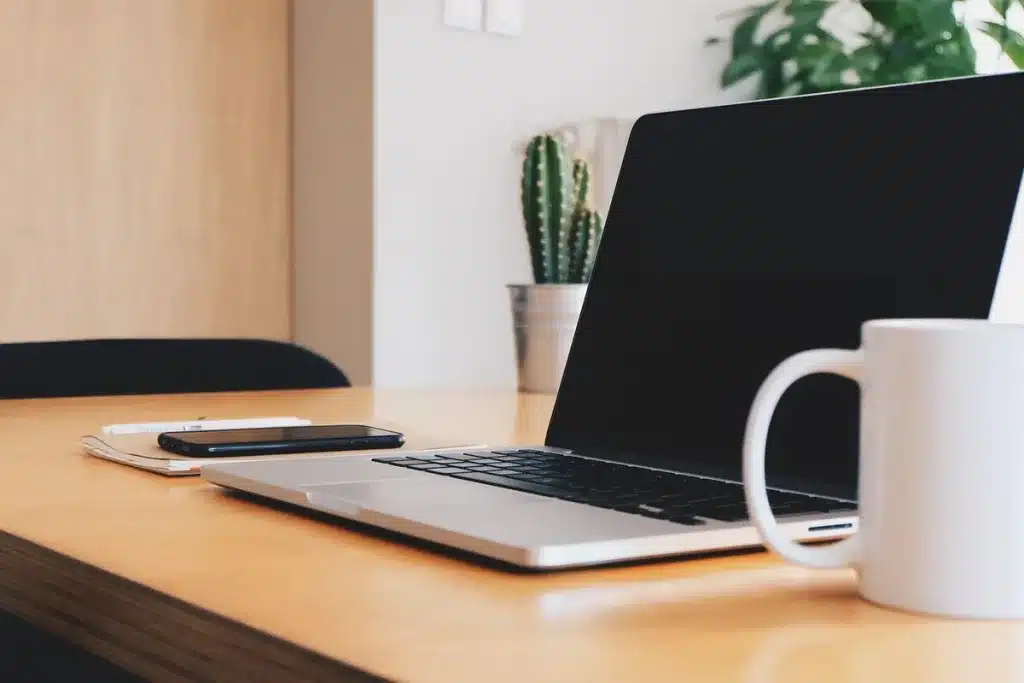 Laptop showing abstract email workflow diagrams, checklist and coffee on a bright office desk