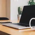 Laptop showing abstract email workflow diagrams, checklist and coffee on a bright office desk