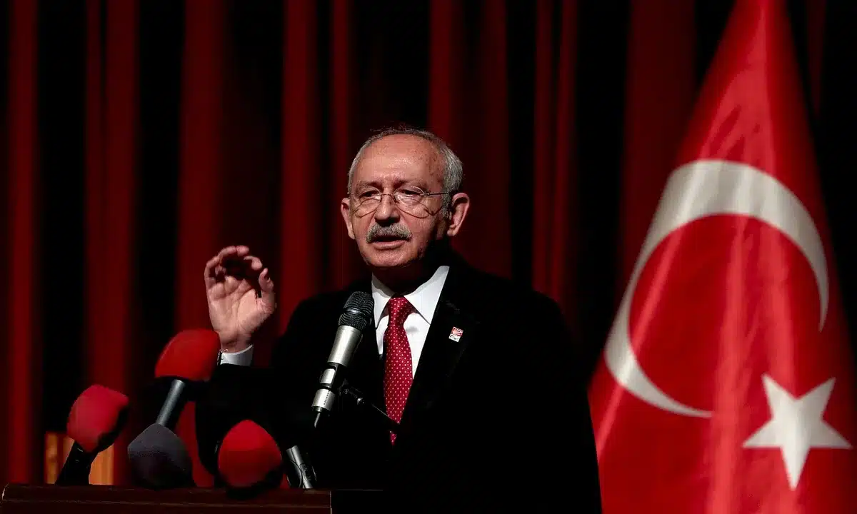 Silhouetted politicians shaking hands at a summit, flags blurred behind